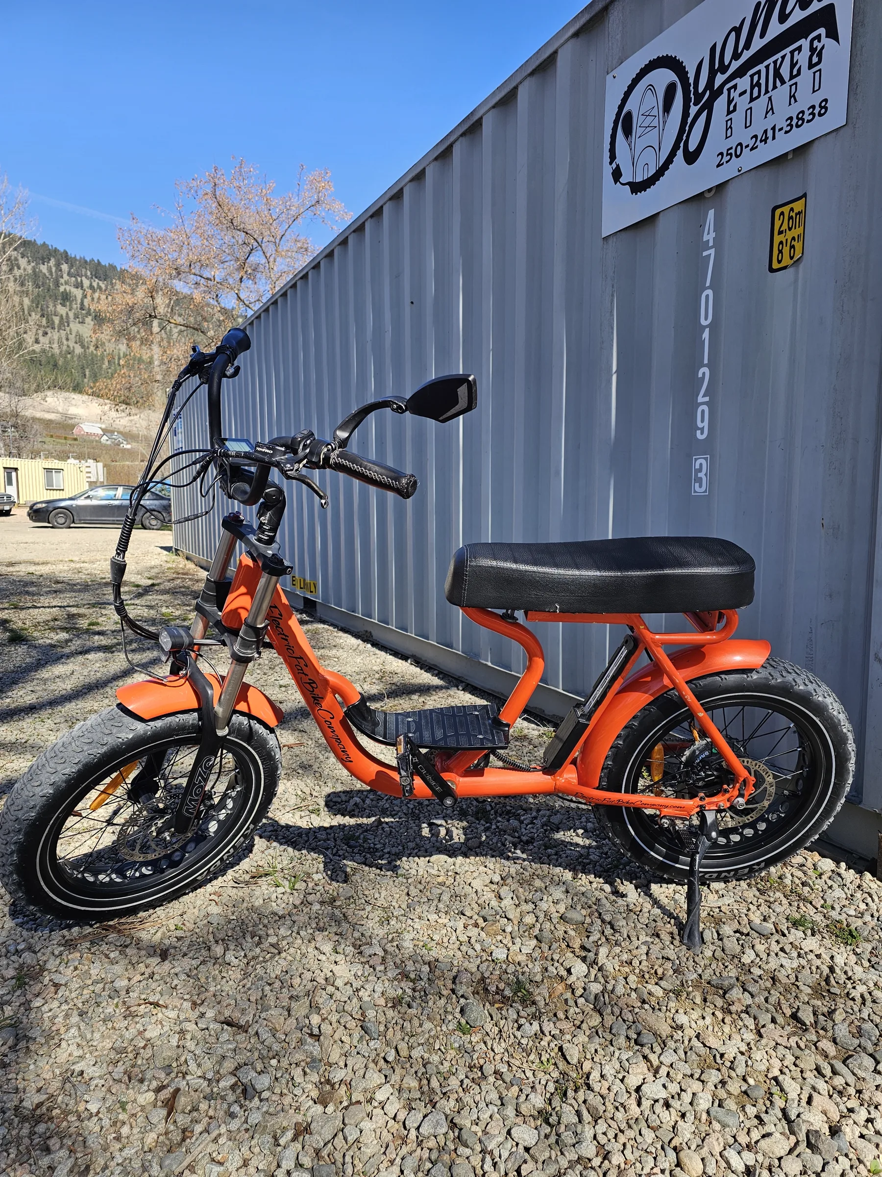 Orange fat-tire Oyama e-bike parked beside the rental shipping container